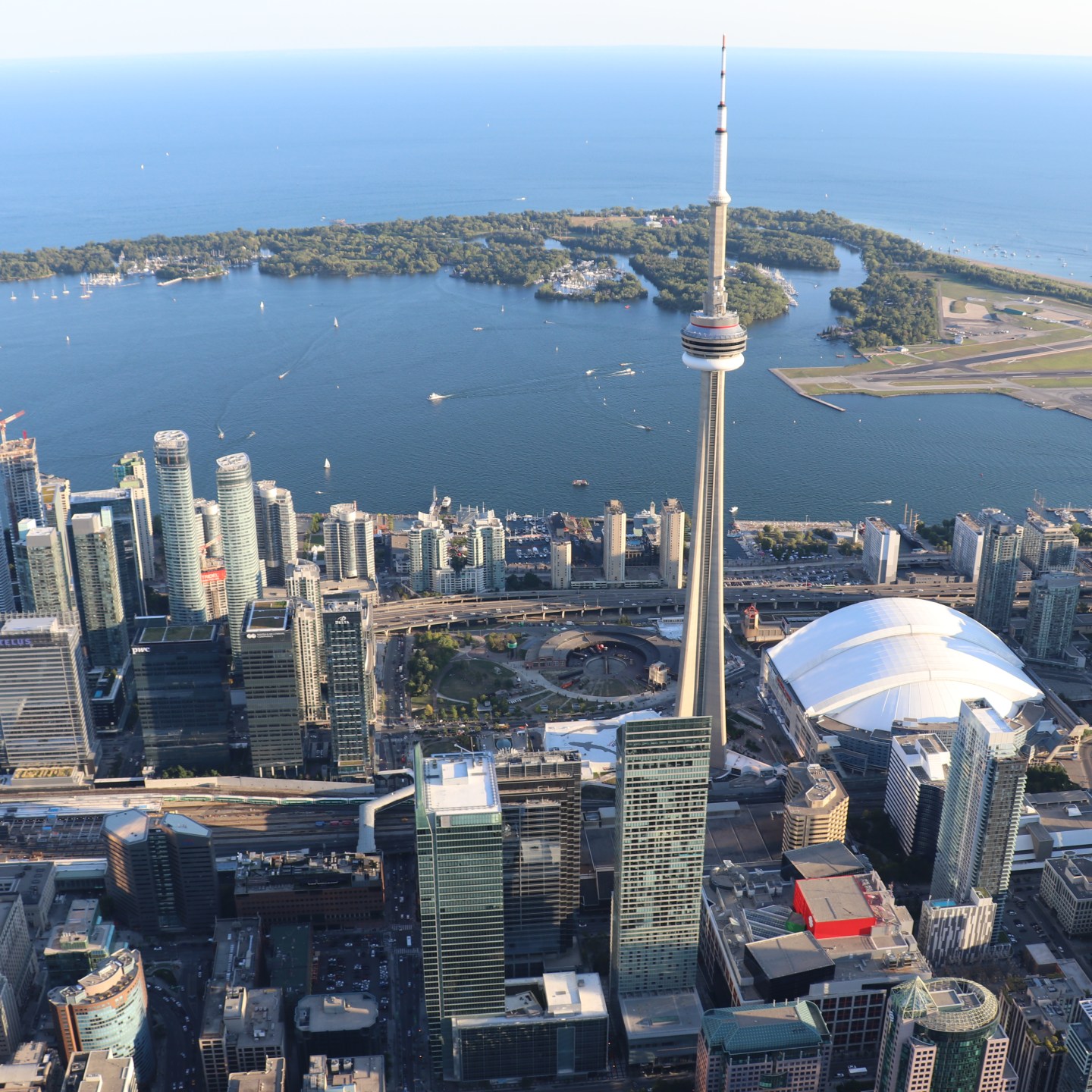 Aerial view of a city skyline with a tall tower and a stadium near a large body of water.