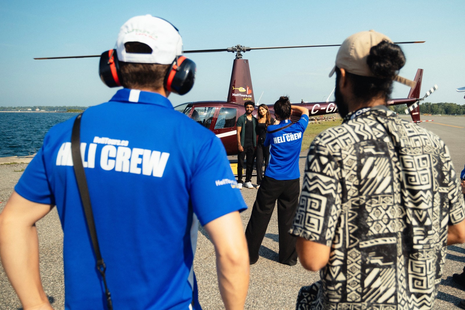 Helicopter crew and group posing by a helicopter near a waterfront.