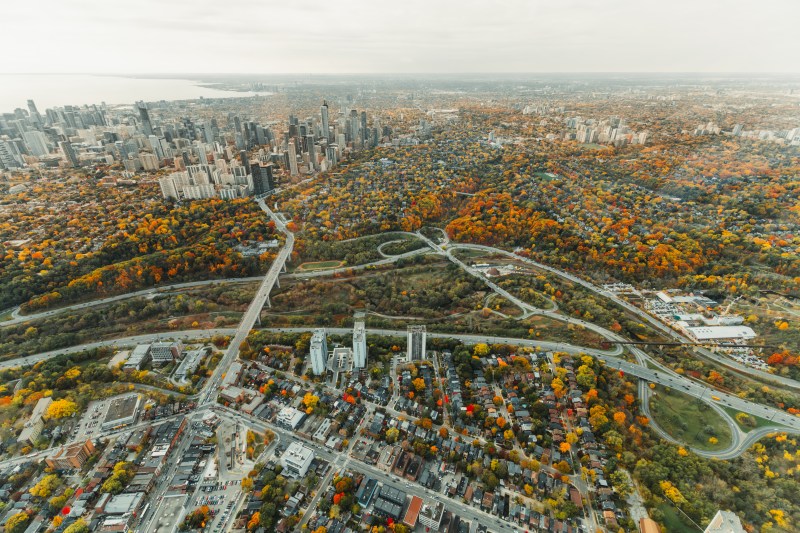 Aerial view of a city with skyscrapers and colorful autumn trees across the landscape.