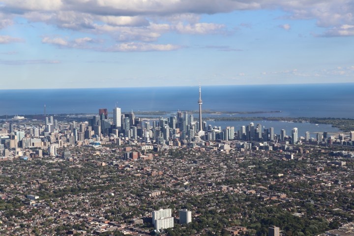 Aerial view of a city skyline with a tall tower and lake in the background.