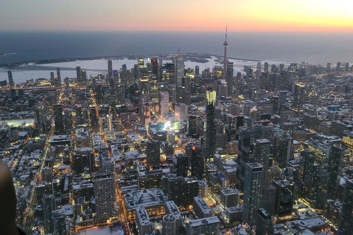 Aerial view of a snowy cityscape with a tall tower at sunset.