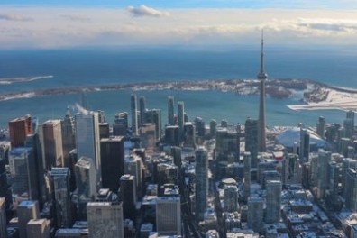 Aerial view of a city skyline with a tall tower and waterfront in winter.