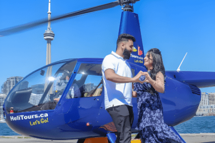 Couple dancing beside a blue helicopter with a cityscape in the background.
