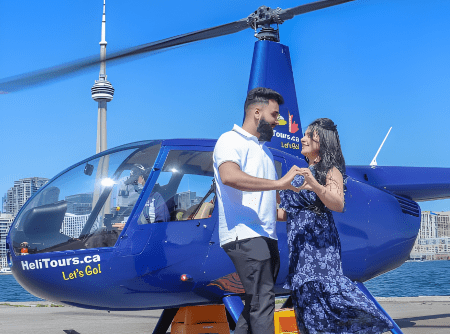 Couple dancing beside a blue helicopter with a cityscape in the background.