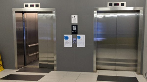 Two elevators, one open and one closed, in a modern building lobby.